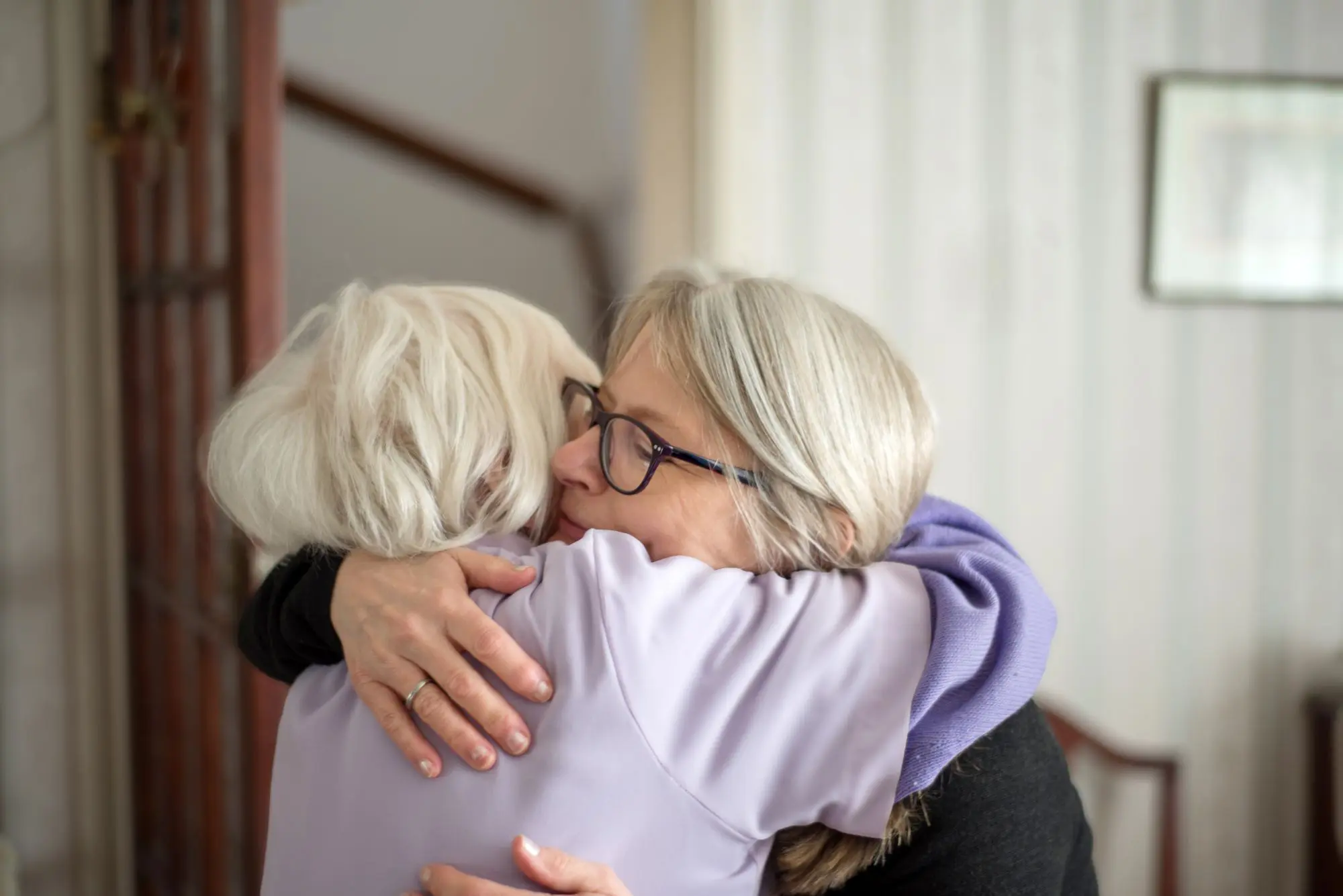 daughter and senior mom hugging in living room
