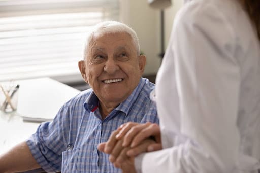senior man with dementia smiling and holding a loved one's hand